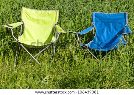 Two empty folding chair on the green grass on a sunny day