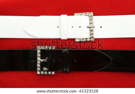 Two leather belts on red fabrics background