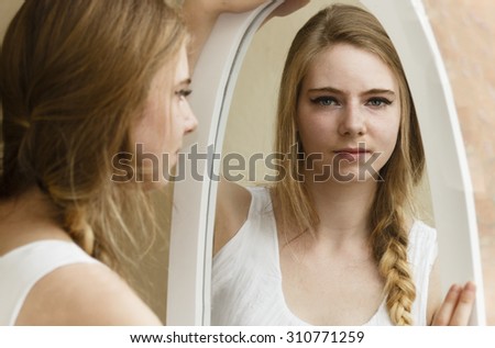 Young woman looking at her reflection in mirror