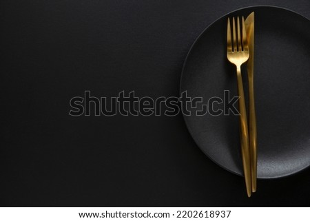 Golden cutlery with textile on plate on dark background. Top View. 