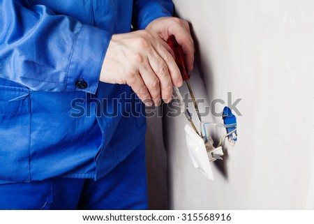 Electrician repairing socket in the house