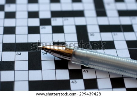 A blank crossword puzzle with a pen lying on top