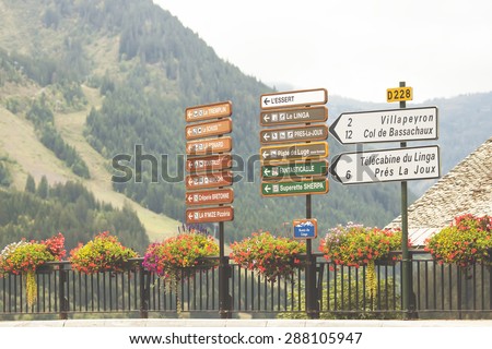 Road signs in Chatel, France showing directions to other chatels and ski resorts: l\'Essert, Le Linga, Piste de Luge, PrÃ© la Joux on the blurred mountain background. selective focus