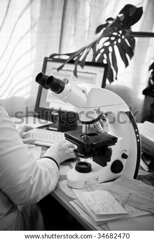 a scientist with a microscope and a case history