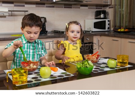 Two children who eat healthy food in the kitchen