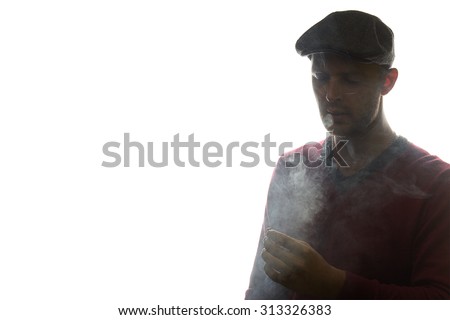 a handsome young man with winter clothes and peaky blinder hat smoking isolated over a white background