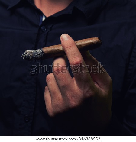 a hand of man holding a cigar