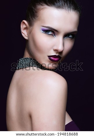 Beauty Woman with Perfect Makeup. Beautiful Professional Holiday Make-up. Purple Lips and Nails. Beauty Girl\'s Face isolated on Black background