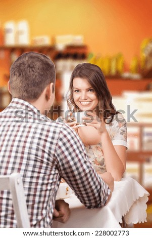 Seducing beautiful woman looking at her lover with coffee cup. Having romantic talk