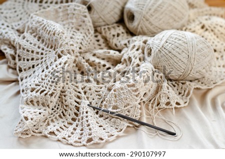 Crochet patterns on the wooden table. Crochet dress from beige yarn.