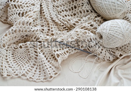 Crochet patterns on the wooden table. Crochet dress from beige yarn.