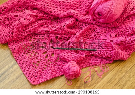Crochet patterns on the wooden table. Crochet of pink yarn.