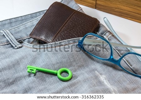 Wallet in a pocket jeans with padlocks green. And blue glasses