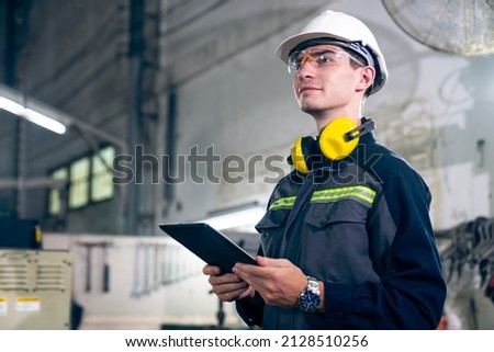 Young factory worker using adept tablet computer in a workshop building . Industrial technology and manufacturing software configuration . Foto stock © 