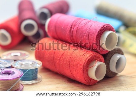 heap of sewing color bobbins threads on wooden table with blur background