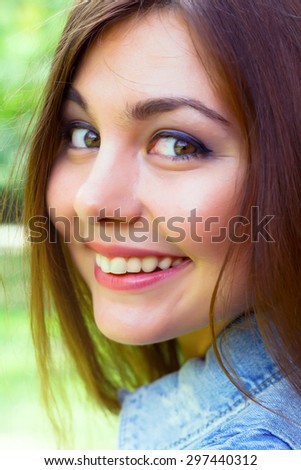 Close up fashion portrait of amazing beautiful woman with brunette curled hairs, natural make up and big green eyes and wide smile with perfect white teeth. Bright colors and positive emotions.
