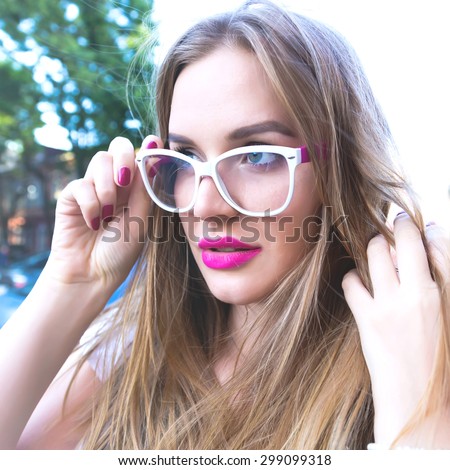 Close up fashion portrait of young blonde woman. Close up fashion portrait of pretty hipster woman with long blonde hairs, wearing stylish trendy clear  glasses, bright colors. Wind,morning.