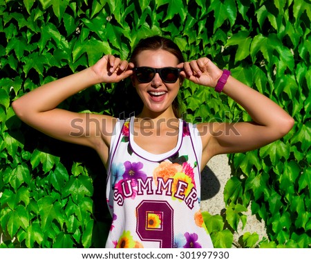 Beautiful girl summer portrait, fashionable young woman,sweat after training.Bright summer trendy portrait of young fit girl posing on the street,wearing bright basketball t-shirt and sunglasses.