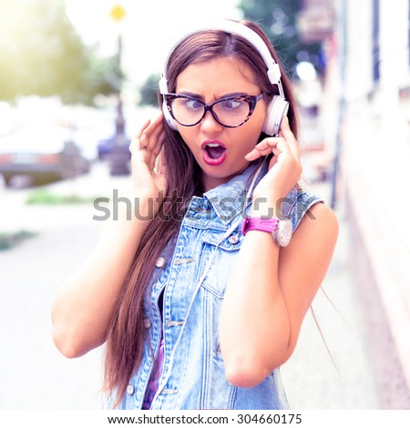 Outdoor street style hipster dj woman in trendy clear sunglasses and headphones listen music and smile.Summer close up Stylish teenage girl listening favorite music and going crazy.Positive emotions