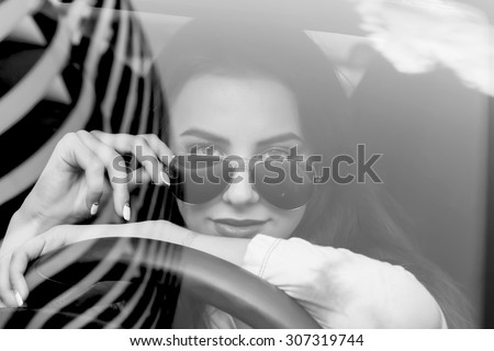 Young woman driving her car.Stylish student girl in car.Summer fashion close up portrait of elegant beautiful woman driving her car in urban city.Black and white image.