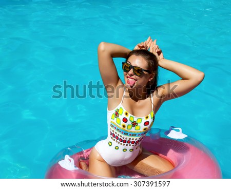Outdoor lifestyle portrait of pretty sexy woman on vacation,wearing bright white bikini , relax and having fun at pool party. Making funny surprised face hands raised up in the form of rabbit ears