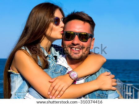 Outdoor closeup fashion portrait of young beautiful couple in summer on the sea pier.Sunset together.Young beautiful couple in love staying on the beach in evening sunshine. Happy smiling boy and girl