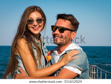 Young valentine couple in love outdoor.Outdoor closeup fashion portrait of young beautiful stylish couple in summer on the sea pier. Fun and smile. Romantic Sunset together.Smiling and hugging.Fun.