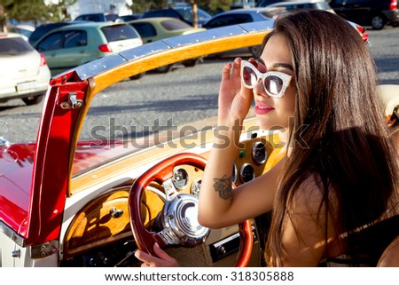 Summer fashion close up  Portrait of beautiful sexy stylish brunette girl model with bright make up driving old retro vintage car.Pin Up girl driving her car.beautiful woman traveling on a vintage car