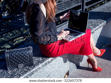 Low body section of a businesswoman using a laptop computer while sitting in a leafy classic city street.Woman hands typing on laptop. young woman browsing internet on her laptop outdoors at the park