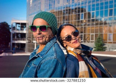 Smiling woman hugging her husband.Fashion close up of Cute couple hugging in the park on a sunny day.Pretty couple hugging and flirting in an urban park,wearing headwear,jeans coat and sunglasses