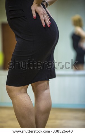 Young blonde woman in stylish black dress making some dance moves