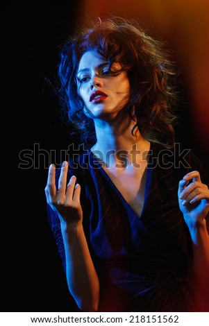 beautiful brunette in the glow of blue and red light. Theatre - a game actor and light