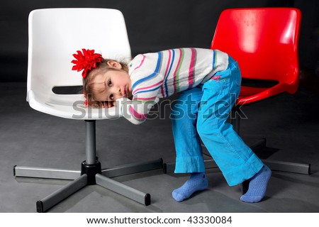 Very sad little girl sits on two chairs