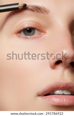 Make-up artist applies brow make-up. Beautiful woman face. Perfect make-up