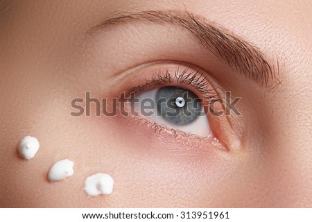 Portrait of young woman with fresh clean face with points of moisturizing  cream under the eye