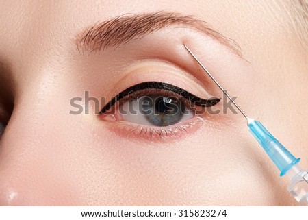 Closeup of beautiful woman gets injection. Beautiful face and the syringe (plastic surgery and cosmetic injection concept).