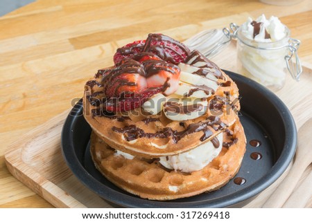 Original waffle with ice cream , banana , fresh strawberry , chocolate sauce and whipped cream , selective focus point.