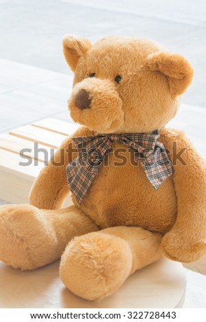 Brown teddy bear sitting on wooden chair , selective focus point and soft light.
