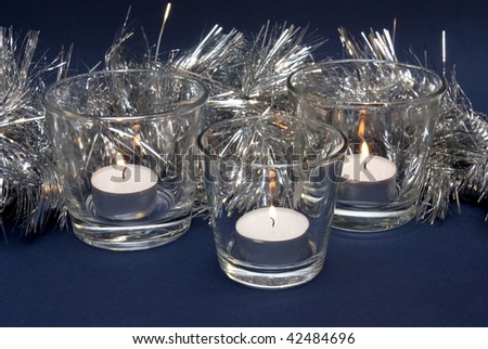 Silvery tinsel and three candles in glass