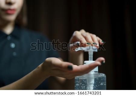 hands using wash hand sanitizer gel pump dispenser. Clear sanitizer in pump bottle, for killing germs, bacteria and virus.