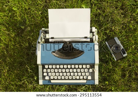 Typewriter and old camera on Grass background