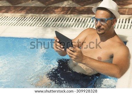 Man using tablet device while relaxing in the hydro massage part of the swimming pool