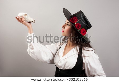Young woman in dramatic artistic image with rose\'s and skull