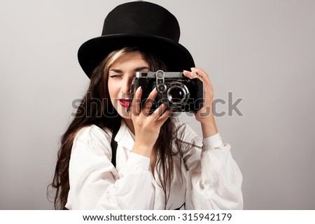 Woman in hat taking photograph from vintage film camera