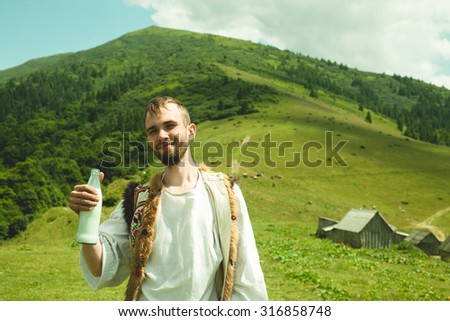 young man wearing traditional clothes with a bottle of milk on a background of mountains