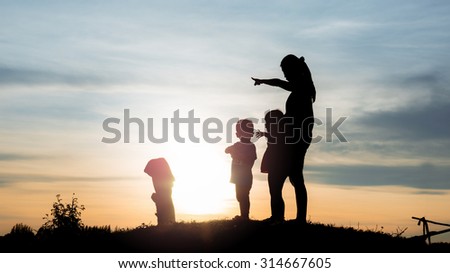 woman and her son and daughter watching sunset