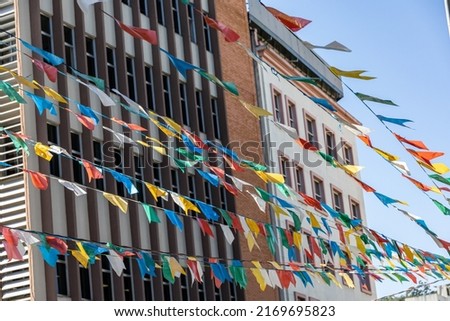 Colorful bright flags are strung on threads. Colored flags on the background of the sky and city buildings. Small flags over the square are flying in the wind. A holiday on a sunny day on the streets  Imagine de stoc © 
