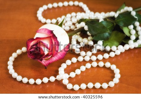 Withered rose with pearls on the table