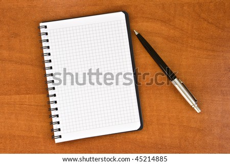 notebook with pen on brown wooden background