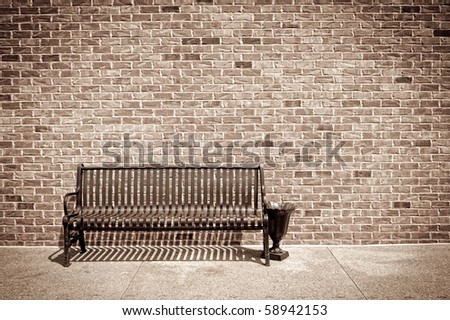 Retro style photo of metal bench against a brick wall